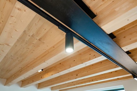 Wooden beam ceiling with black rail spot, warm light and modern, quiet atmosphere, house
