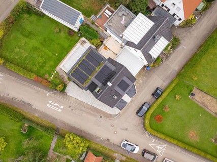Aerial view of a residential area with house and photovoltaic, green gardens and traffic-calmed
