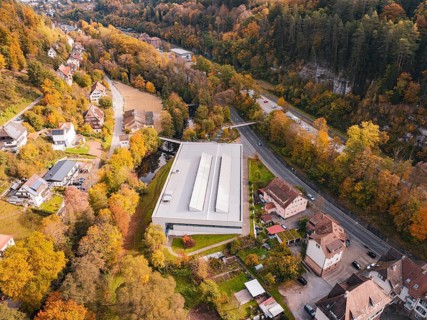 Sports hall located in an autumn landscape with surrounding forest and nearby roads, Walter Lindner