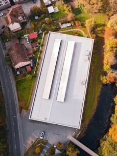 Aerial view of a sports hall with a flat roof surrounded by colorful autumn vegetation, Walter