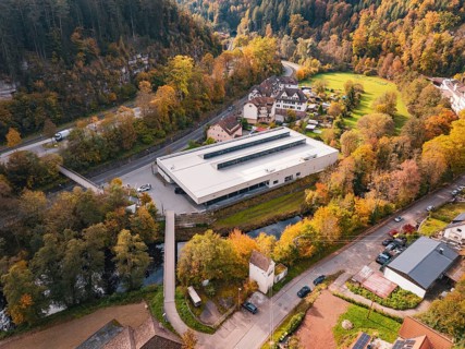 Sports hall in a valley landscape, surrounded by thick forests and a small river, Walter Lindner