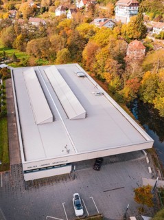 Flat roof of a sports hall surrounded by autumn-colored trees and nearby houses, Walter Lindner