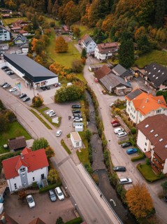 Aerial view of a small village in autumn with colorful trees, roads, buildings and a small river,
