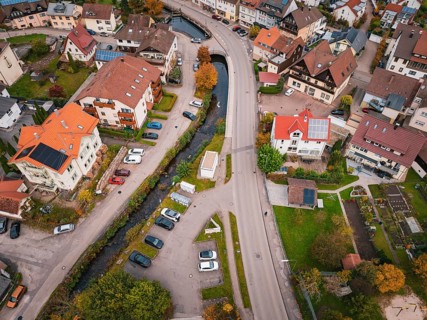 Urban aerial view of an area with a river, parked cars and lush autumn leaves, Calmbach, Bad