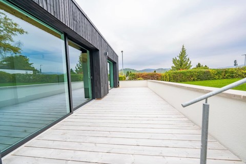 Wide terrace with wooden flooring and views of the countryside under overcast sky, house