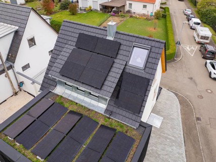 Close-up of anthracite-colored gable roof with several PV fields, skylight and fireplace, house