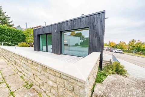 Contemporary extension with large glass front and terrace over a natural stone wall, house
