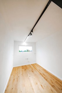 Narrow, bright room with light rail and oak floor, a window with connections at the back, house