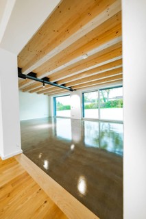 Open space with wooden ceiling, steel girders and polished concrete floor, transition from parquet