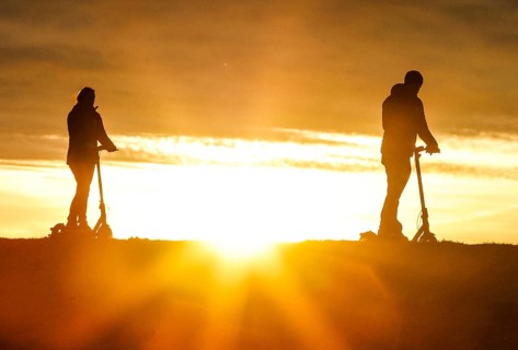 E-scooter drivers ride across a dike on the island of Fehmarn at sunset, 13.10.2025, Fehmarn,