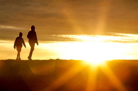 Woman and child walk across a dike on the island of Fehmarn at sunset, 13.10.2025, Fehmarn,