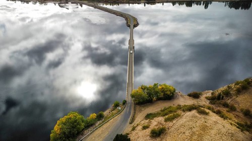 A long bridge over a shallow and calm lake on a cloudy day, photographed with a drone
