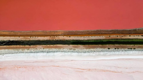 Pink lake next to the xoast, divided by streams and streets, photograped with a drone
