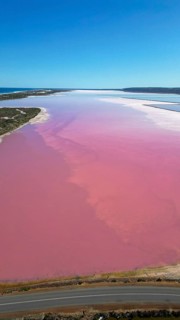 Pink lake next to the xoast, divided by streams and streets, photograped with a drone