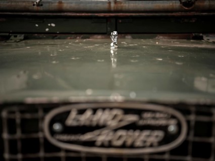 The front end of a 1950's Series One Land Rover, with a small hood ornament, parked at the Toronto