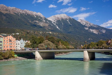 Colourful row of houses in Mariahilfstraße on the Inn River, Inn Bridge and mountains of the