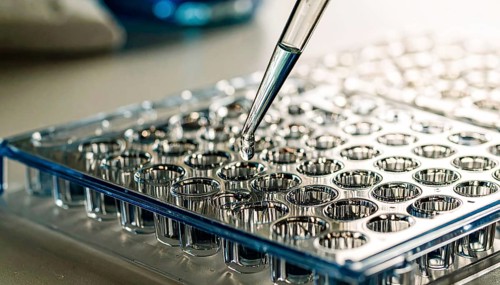 Blue-tinted droplet about to land in a clear microplate, calm clinical atmosphere, Pipette