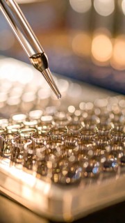 Pipette hovers over gleaming microplate wells amid a warm amber glow, Pipette dispensing a liquid