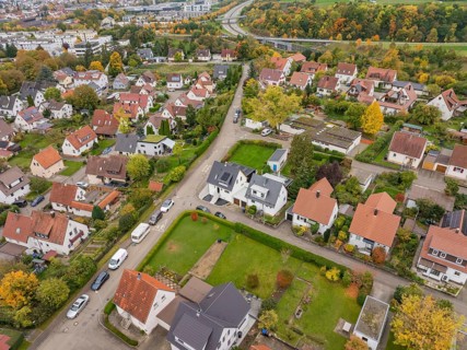 A panoramic view of a quiet suburban settlement with allotments and a winding highway in autumn