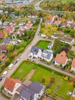 Suburban road with single-family houses and autumn gardens, a motorway in the background,