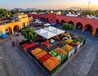 Traditional Mexican plaza with crates of peppers, onions, and tomatoes, economic prosperity in