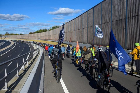 Cyclists on their way to the 16th construction phase of the A100. Flags from adfc and Respect