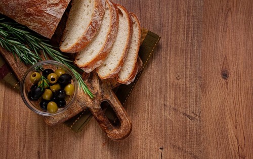 Sliced ciabatta, on a chopping board, with rosemary and olives, Italian bread, close-up, Italian
