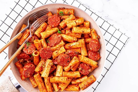 Rigatoni pasta with spicy sausage, and rich tomato sauce served, on a white plate, homemade