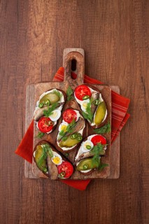 Sandwiches on rye bread with sprats, quail eggs, fresh tomatoes and pickled cucumber, on a wooden
