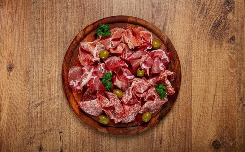 Assortment, sliced meat appetizer, prosciutto, salami and ham, with olives, on a wooden board,