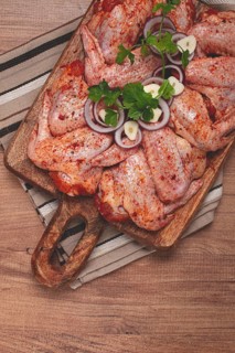 Chicken wings, marinated and laid out on a wooden platter, ready for cooking, grilling or baking,