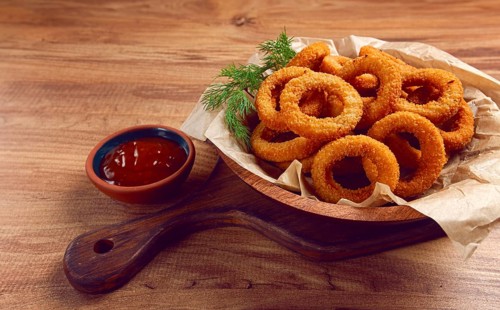 Deep fried onion rings, appetizer, with tomato sauce, on a wooden table, no people, favorite dish