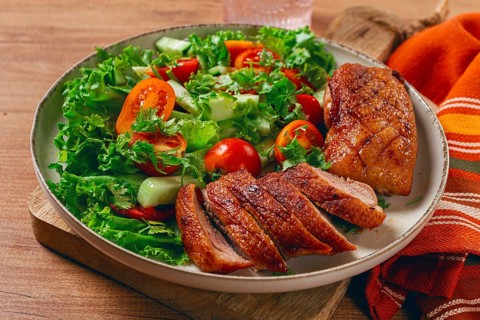 Delicious grilled duck breast served with fresh garden salad and cherry tomatoes at a rustic dining