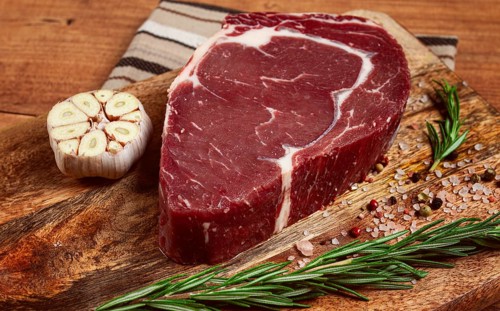 Raw steak, beef steak, rib eye steak, on a cutting board, freshly frozen, with spices and herbs, on