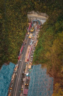 Aerial view of a rail building with tunnel opening and construction work in autumn forest,