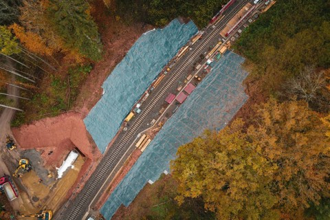 Railway line from above, surrounded by autumn colors, with construction work on the tracks,