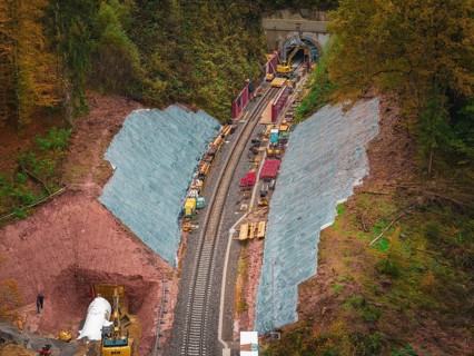 Working at the tunnel entrance to a railway line, with construction equipment and soil in an autumn