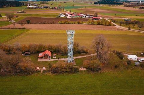 View of an observation tower in a rural area with fields and a village in the background,