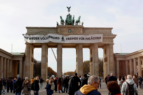 Several activists drop a banner with the inscription Never again genocide, freedom for Palestine