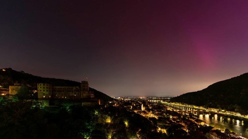 Nocturnal sky with aurora borealis over Heidelberg. Heidelberg Castle on the left, the Neckar river