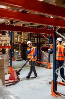 Diverse team of warehouse workers communicating while managing inventory and moving goods with a