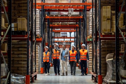 Manager discussing inventory and operations with his diverse team of warehouse workers wearing