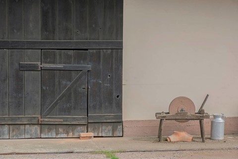 A whetstone and a bucket in front of an old rustic barn door, Hohwiller, Alsace, France