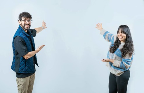Happy couple showing something and smiling at the camera, isolated. Young couple presenting