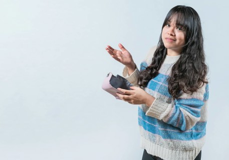 Worried person showing empty wallet isolated. Portrait of bankrupt Asian woman showing empty wallet