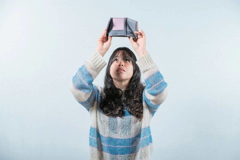 Young woman shaking her empty wallet. Worried girl with no money holding empty wallet, isolated