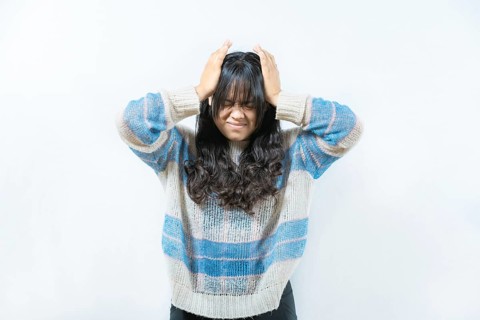 Unhappy woman with headache isolated. Painful girl with migraine holding his head isolated