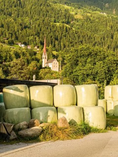 Agricultural structures with hay bales sealed in plastic near a farm on the outskirts of Oetz in