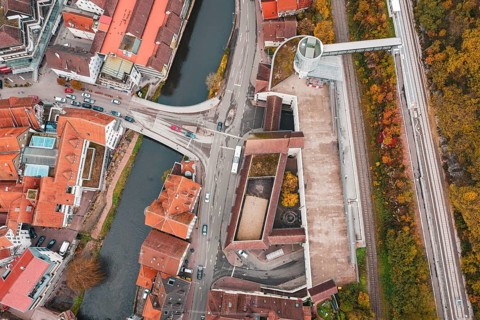Aerial view of a city with a river and bridges, surrounded by autumn-colored trees, ZOB Calw,