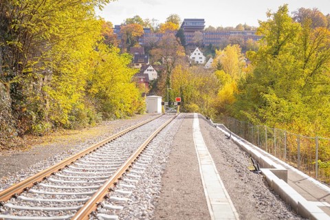 Railway track leads through autumn landscape with buildings in the background, ZOB Calw, Hermann